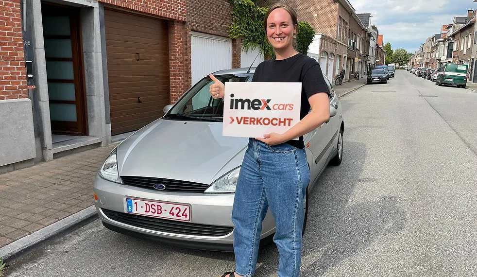 Verkoper met Imex Cars ‘VERKOCHT’ bord bij verkochte wagen – verkoop je auto in België